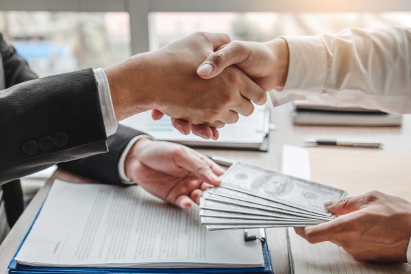 businessman-shaking-hands-giving-dollar-bills-corruption-bribery-business-manager-deal-contract